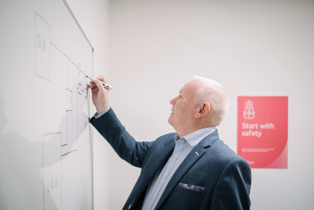 Exilux employee writing on a white board showing emergency lighting diagrams